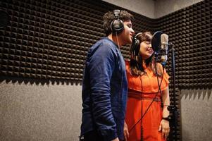 Young asian duet singers with microphone recording song in record music studio. photo