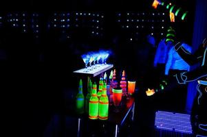 Professional barman and led light fire show. Silhouette of modern bartender shaking drink at night cocktail bar. photo