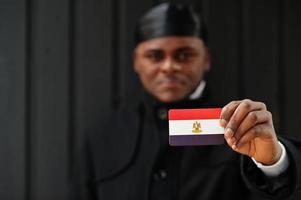 African man wear black durag hold Egypt flag at hand isolated dark background. photo