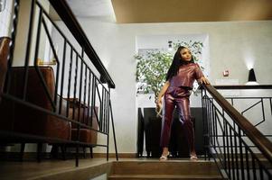 Beautiful african american woman in red leather costume pose at restaurant. photo