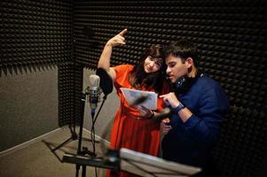 jóvenes cantantes de dúo asiáticos con micrófono grabando una canción en un estudio de grabación de música. foto