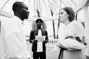 Wedding engagement ceremony with pastor. Happy multiethnic couple in love story. Relationships of african man and white european woman. photo