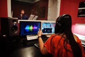 Young asian singer man with microphone recording song in record music studio with sound producer. photo