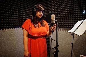 Young asian singer with microphone recording song in record music studio. photo