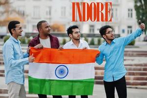 inscripción de la ciudad de indore. grupo de cuatro amigos varones indios con la bandera india haciendo selfie en el teléfono móvil. concepto de ciudades indias más grandes. foto