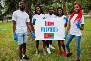 grupo de voluntarios africanos felices se mantienen en blanco con la bandera de eritrea en el parque. Concepto de voluntariado, caridad, personas y ecología de los países africanos. foto