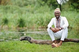 Portrait of african man in traditional clothes at park. photo