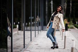 Fashionable african american woman wear beret and coat with handbag posing outdoor. photo