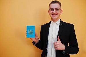 Young handsome man holding Republic of Fiji passport id over yellow background, happy and show thumb up.  Travel to Oceania country concept. photo