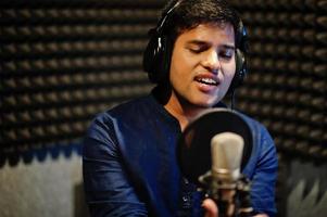 joven cantante asiático con micrófono grabando una canción en un estudio de grabación de música. foto