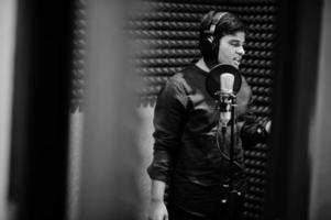 joven cantante asiático con micrófono grabando una canción en un estudio de grabación de música. foto