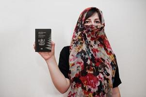 una joven musulmana árabe vestida con hiyab tiene pasaporte de nueva zelanda con fondo de pared blanca, retrato de estudio. foto