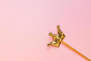 palo mágico dorado de lentejuelas en forma de corona sobre fondo rosa pastel. plano creativo en estilo minimalista foto