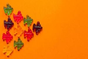 Jelly sweets, colorful marmalade airplanes on oarange background. Open pattern photo