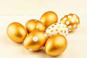 Easter festive decoration.Close up of easter eggs colored with golden paint on wooden background. Various dotted designs photo