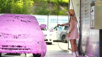 jong vrouw in roze jurk en rietje hoed wast een auto video