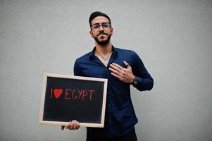 I love Egypt. Middle eastern man wear blue shirt, eyeglasses, hold board. photo