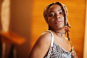 Lovely african american woman with dreadlocks in leopard outfit at cafe. Beautiful cool fashionable black young girl indoor. photo