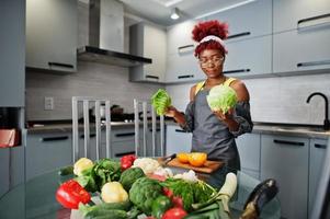 African american woman preparing healthy food at home kitchen. She hold a cabbage. photo