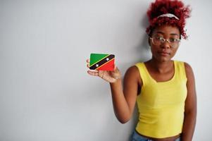 African american woman with afro hair, wear yellow singlet and eyeglasses, hold Saint Kitts and Nevis flag isolated on white background. photo