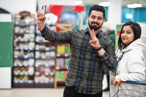 pareja asiática usa compras juntas en el supermercado, haciendo selfie por teléfono. foto