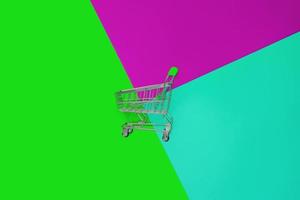 Top view of empty shopping trolley on colorful bright background. Concept of shopping and consumerism. Minimal flat lay. photo