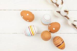Festive easter background. Cotton flower branch and painted eggs on wooden background. Neutral colors photo
