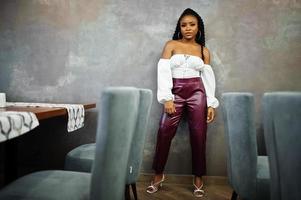 Beautiful african american woman in white blouse and red leather pants pose at restaurant. photo