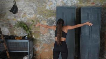 Young fit woman with long dark ponytail seen from behind stretches arms and upper body video