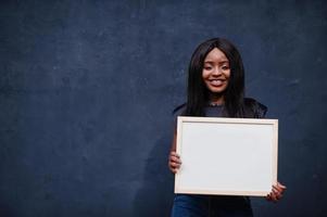 mujer africana de moda sostiene una pizarra blanca vacía. foto