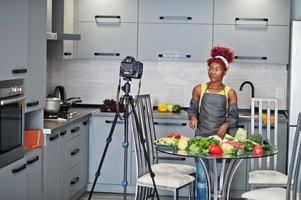 mujer afroamericana filmando la transmisión de su blog sobre comida saludable en la cocina de casa. foto