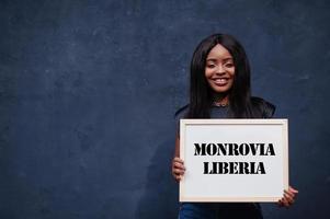 African woman hold white board with Monrovia Liberia inscription. Most populous city in Africa concept. photo
