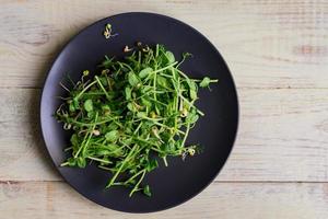 Top view of vegan healthy salad made of peas microgreen sprouts and sprouted beans on wooden background photo