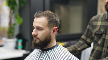 Barber trims hair of male client with comb and clippers