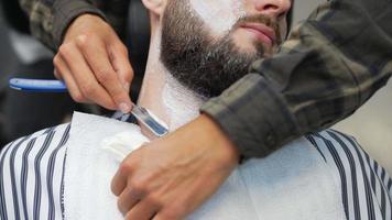 Male barber shaves man's neck with straight razor blade video