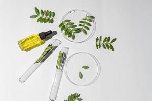 top view of cosmetic essential oil in glass bottle and petri dish and test tube on a table. lab research on skin care cosmetic ingredients and product safety. photo