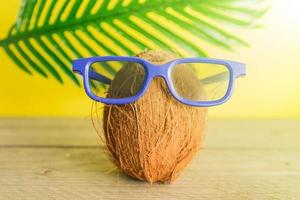 A cocnut wearing 3D glasses on blue background. Summer and trave concept photo