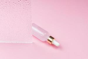 Skin care essence oil dropper glass bottle on pink background. Hydrating serum, vitamin for face skin. Aesthetic, minimalism. photo