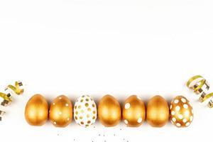 Easter festive decoration.Top view of easter eggs colored with golden paint on white background. Various dotted designs photo