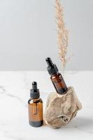 amber bottles for essential oils and cosmetics stand next to the stone. Glass bottle. Dropper, spray bottle. Natural cosmetics concept with trendy natural materials. Unbranding packaging photo
