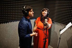 Young asian duet singers with microphone recording song in record music studio. photo