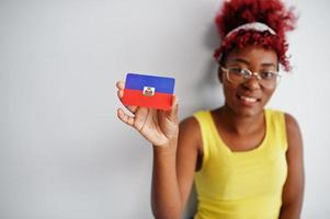 African american woman with afro hair, wear yellow singlet and eyeglasses, hold Haiti flag isolated on white background. photo