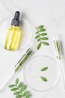 Laboratory glassware and pipette bottle with serum and oil on marble background. Natural medicine, cosmetic research, bio science, organic skin care products. Concept skincare. photo