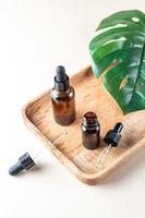 Hyaluronic acid oil mockup with collagen and peptides in brown bottles on wooden tray with green monstera leaf. Skincare beauty product liquid cosmetic serum packaging. Organic science concept photo