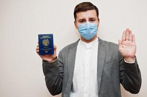 European man in formal wear and face mask, show Armenia passport with stop sign hand. Coronavirus lockdown in Europe country concept. photo