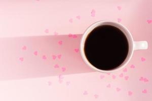 Morning Pink cup of tea on pink background with scattered paper hearts. Love and care concept. Copy space for text photo