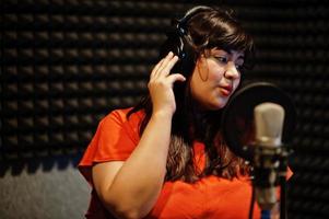 Young asian singer with microphone recording song in record music studio. photo