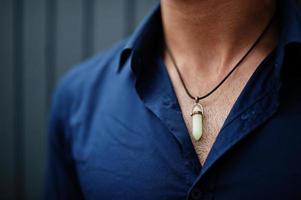 Close up hexagon point quartz pendant at man. photo