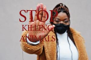 Stop killing animals. African american woman, wear black face mask show stop hand sign. photo