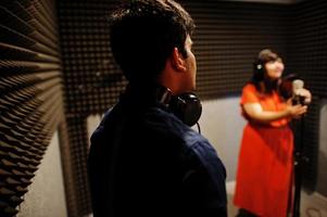 Young asian duet singers with microphone recording song in record music studio. photo